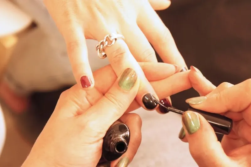 Olive-green nail polish being applied to a client's nails